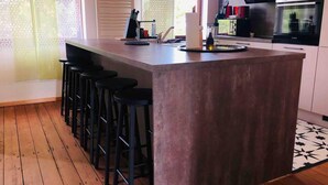 Une cuisine dotée d’un îlot central, de tabourets de bar, d’une cuisinière et d’un four à micro-ondes.