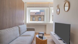 Una sala de estar moderna con un sofá, un televisor y una ventana con persianas.