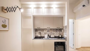 A compact kitchen with white cabinetry, a tiled backsplash, and a built-in oven.