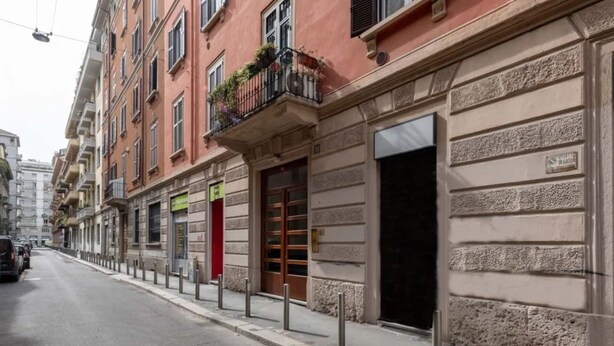 A street view of a row of buildings with a red door and a sign indicating a business establishment.