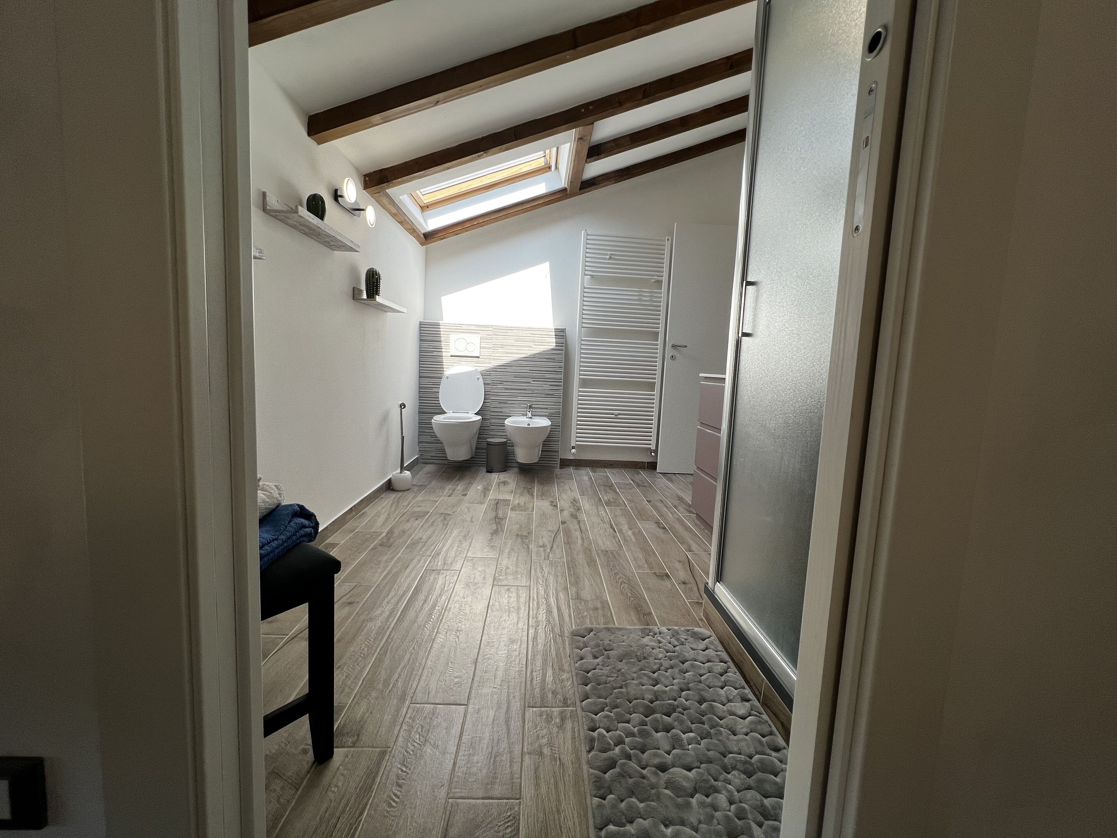 Une petite salle de bain comprenant des toilettes, un bidet et une petite étagère ornée d’objets décoratifs.