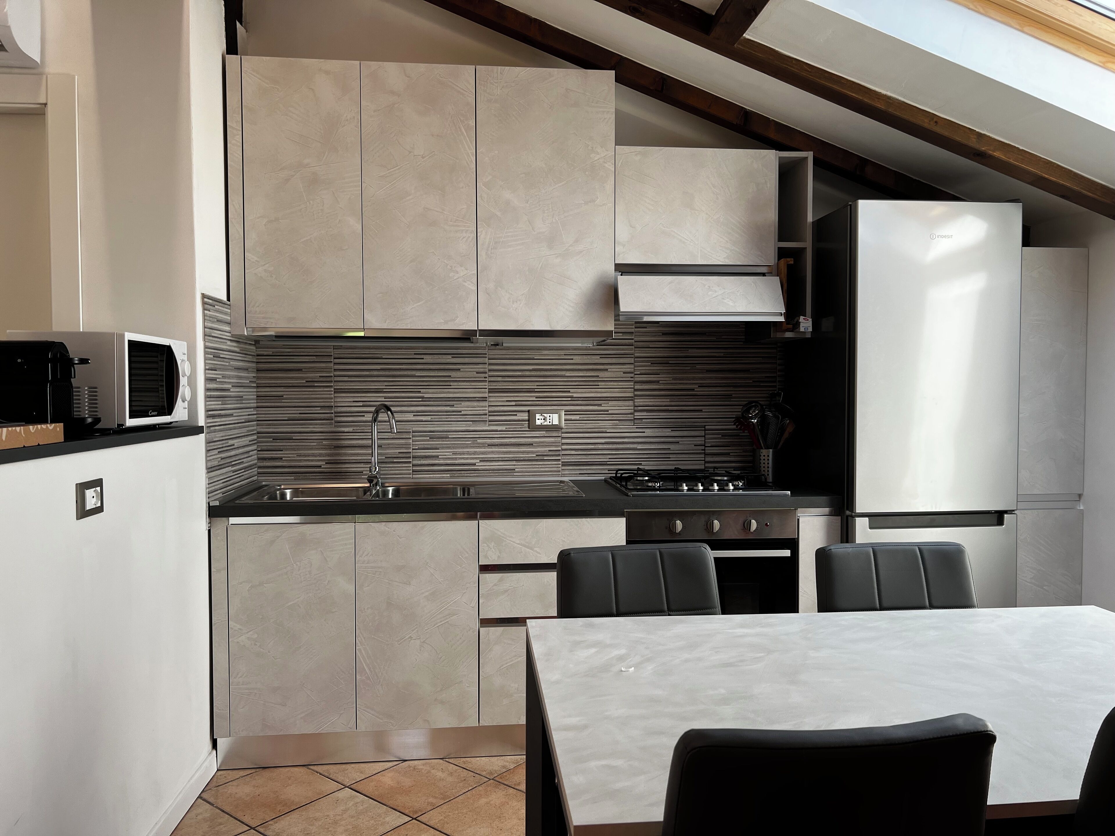 Une cuisine moderne équipée d’une cuisinière intégrée, d’un évier et d’un coin repas avec une table et des chaises.