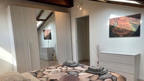Un dormitorio con cama, cómoda, un cuadro y espejo.