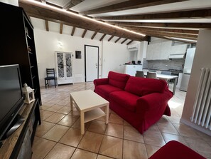 A modern living room with a red sofa, a small white table, and a TV stand. - Apartment in country villa with traditional DOP vinegar cellar (Ravarino)