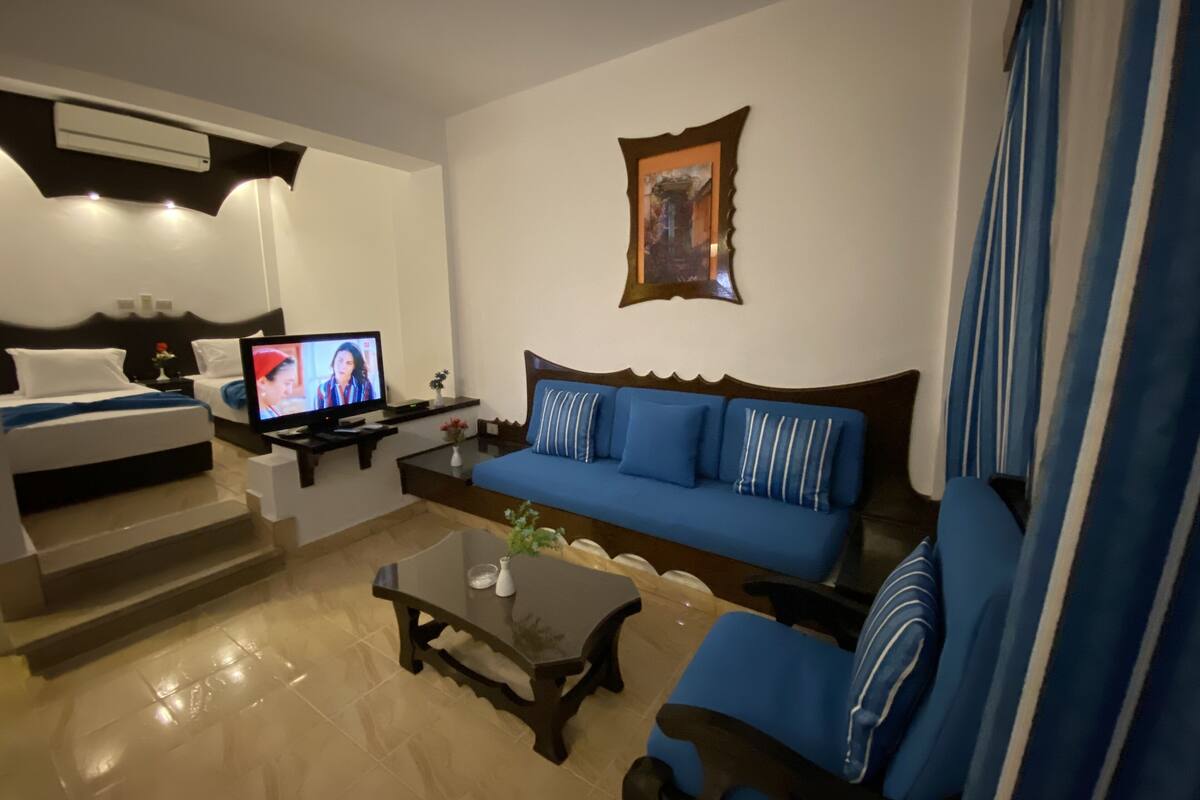 Una sala de estar moderna con un sofá azul, un televisor, una mesa de centro y un cuadro decorativo en la pared.