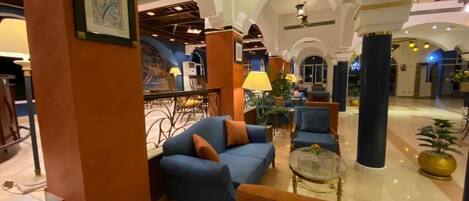 A lobby with a blue sofa, a glass coffee table, and a staircase.
