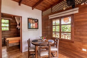 A wooden interior with a round table, chairs, a bench, and a wall-mounted picture. - Casa Toty (Limon)