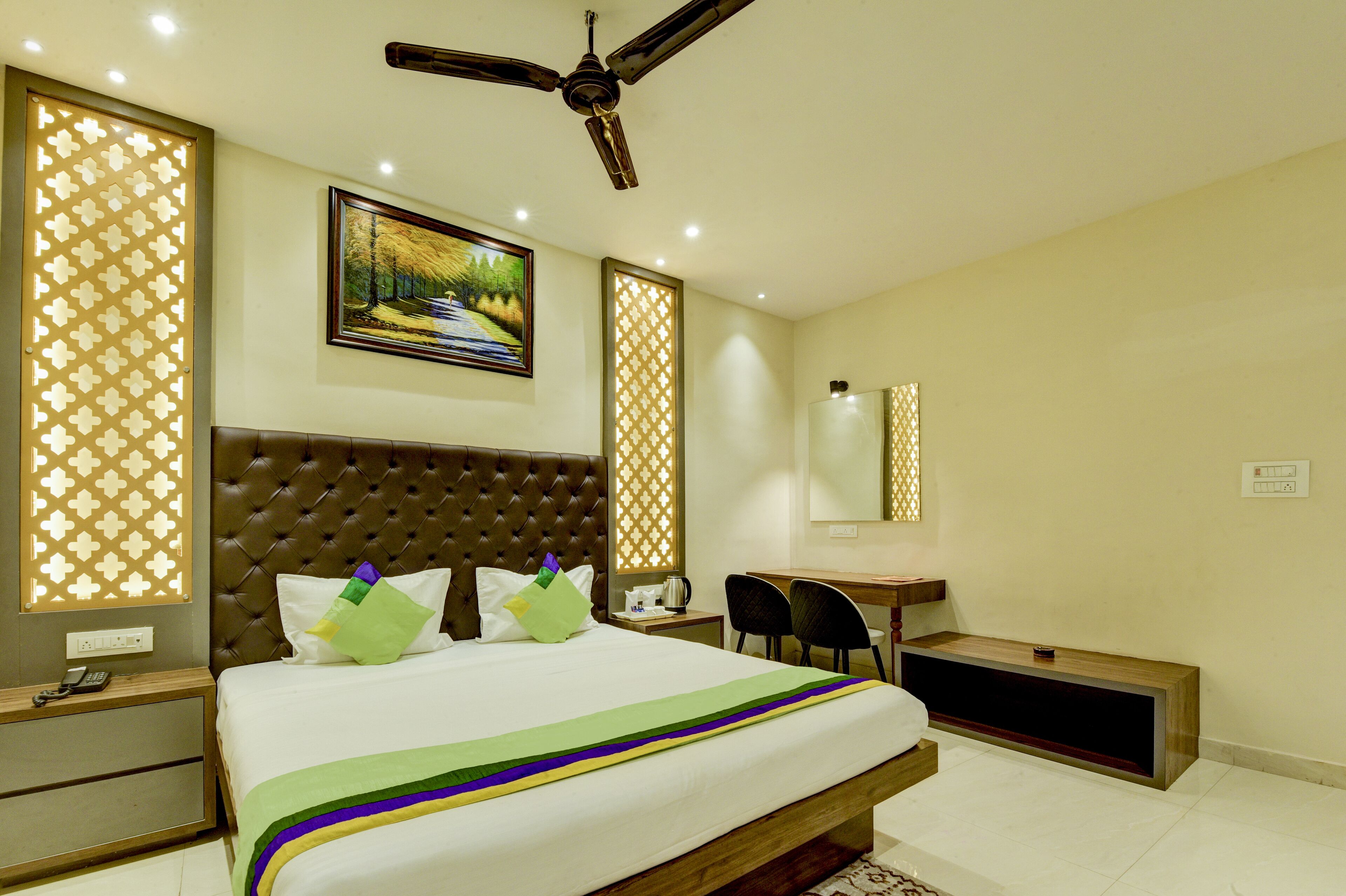 A hotel room with a large bed, a desk, and a ceiling fan.