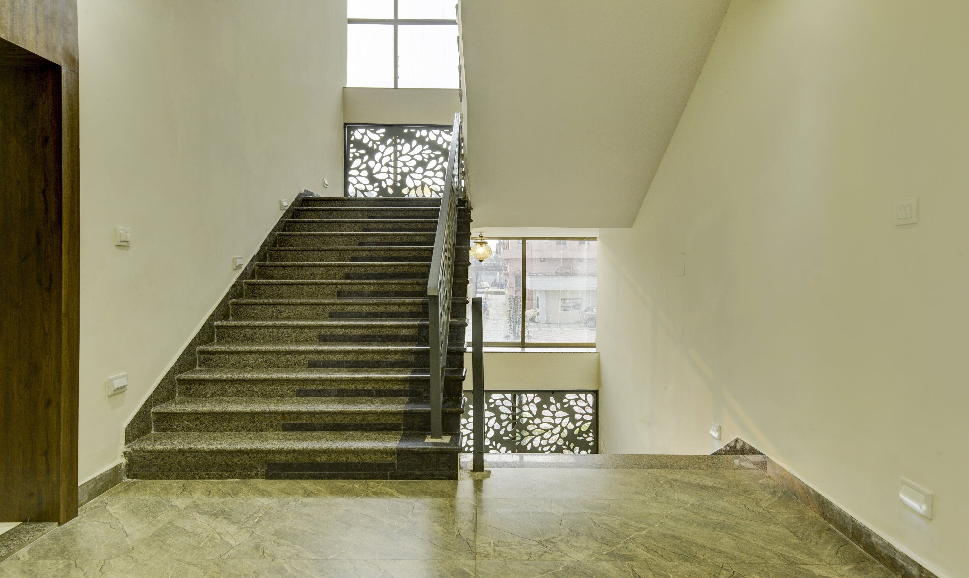 A staircase with a wooden handrail and a view of the street through a window.