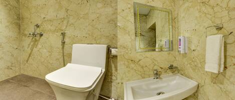 A bathroom with a toilet, shower, sink, and a mirror.