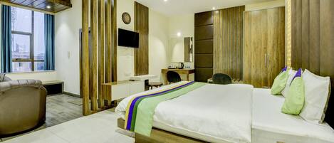 A modern hotel room with a large bed, a desk, a chair, and a wardrobe.