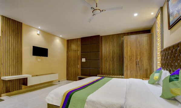 Une chambre moderne comprenant un lit, un téléviseur à écran plat, un lambris en bois, un ventilateur de plafond et une grande armoire.