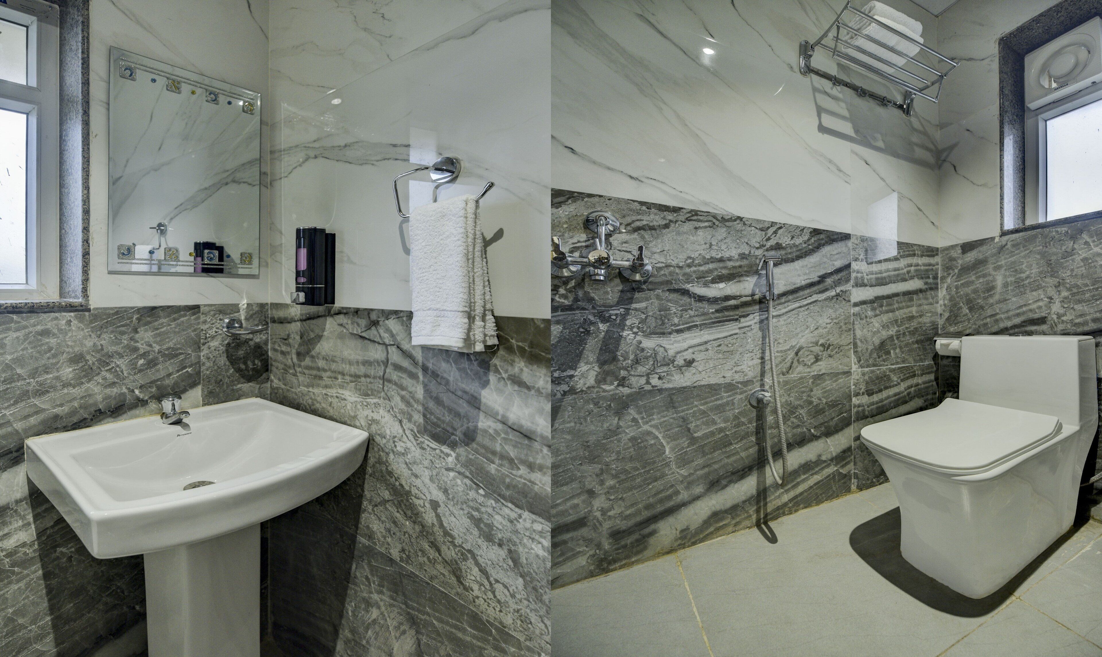 A bathroom with a marble vanity, a shower with a handheld showerhead, and a toilet.