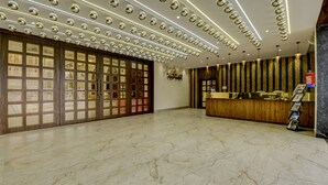 Un hall espacioso con suelo de mármol, una recepción y una pared con cuadros enmarcados.