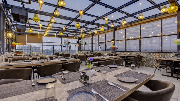 Un restaurante con varias mesas, sillas e iluminación colgante.