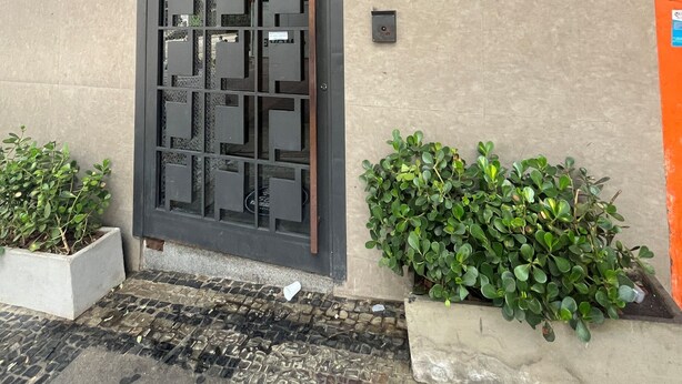 A building entrance with a large decorative door, a sign with a logo, and potted plants. - Samba Belo Horizonte Vintage (Belo Horizonte)