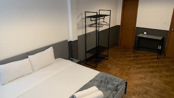 Habitación de hotel con cama, escritorio, armario y perchero.
