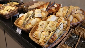 A buffet with various breads and pastries displayed in baskets. - Samba Belo Horizonte Vintage (Belo Horizonte)
