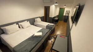 A hotel room with two beds, a desk, a chair, a TV, and a green door. - Samba Belo Horizonte Vintage (Belo Horizonte)