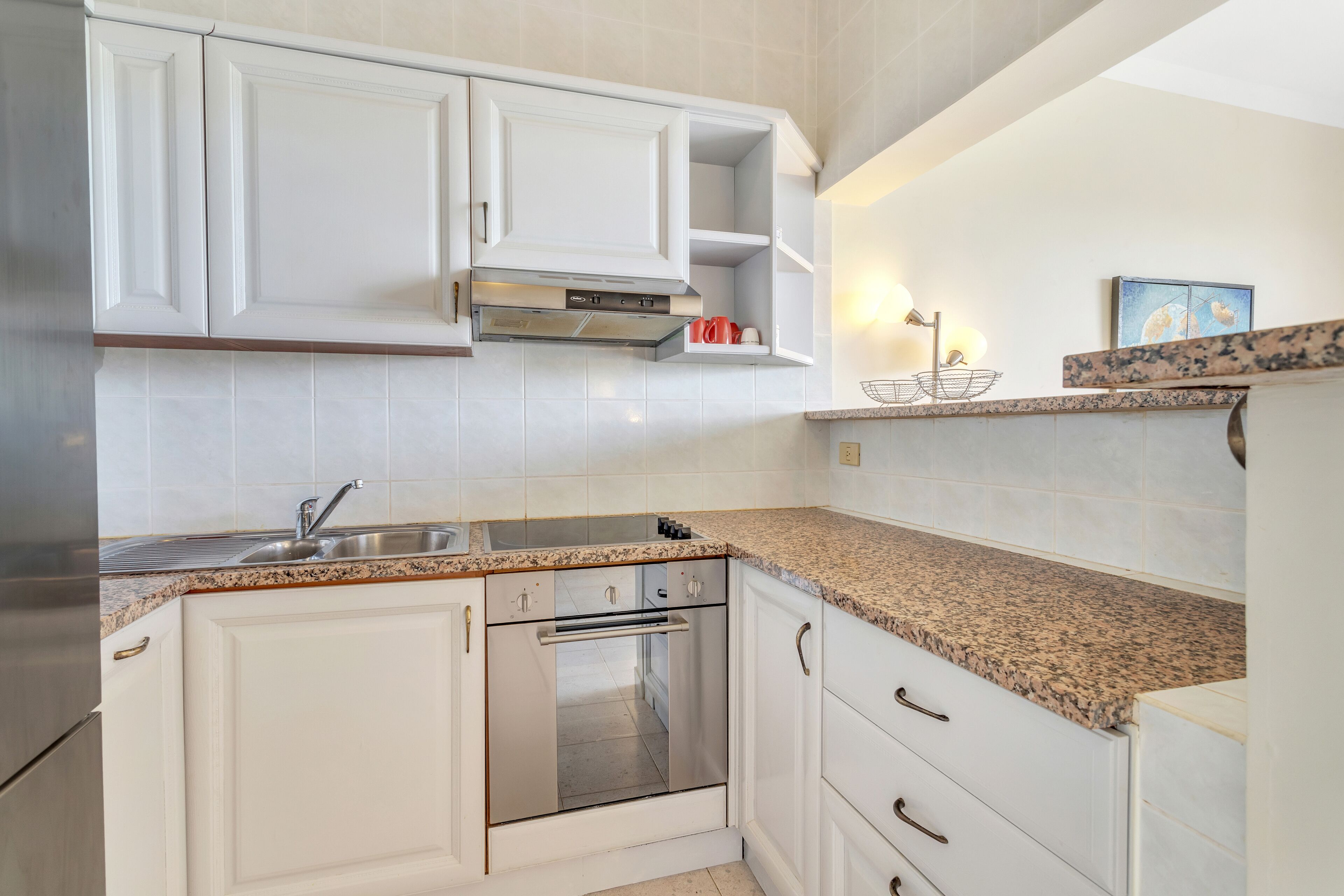 A kitchen with white cabinets, a stainless steel oven, a granite countertop, and a built-in microwave.