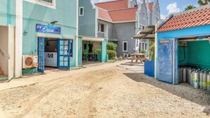 A street with buildings, including a blue building with a sign reading "DIV OCEAN Diving Center". - Caribbean Court - Harbor View Apartment (Kralendijk)