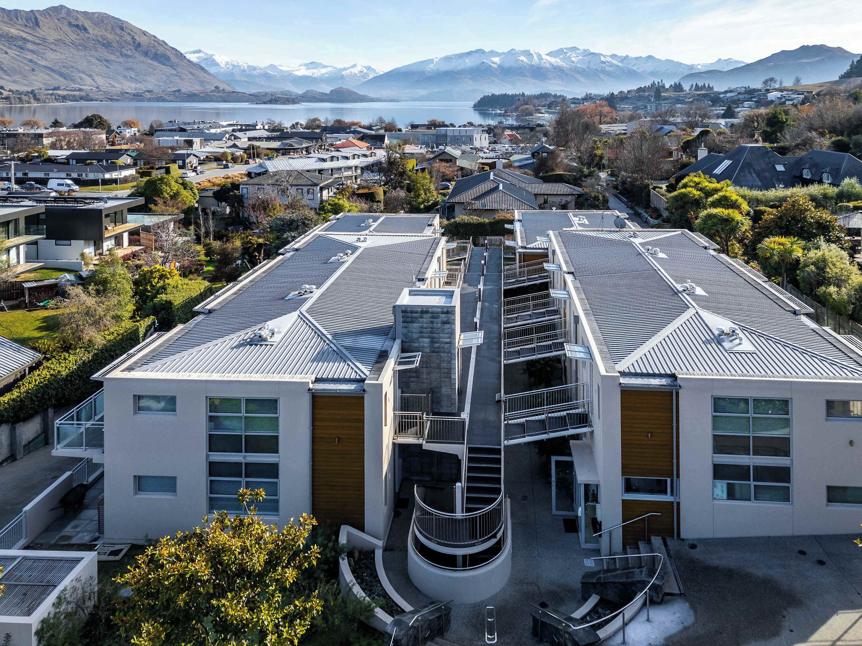 A modern building with a central spiral staircase, large windows, and a view of a lake and mountains in the background.