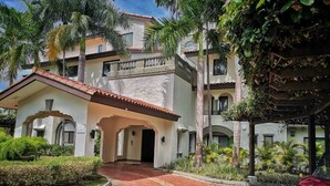 A building with a red-tiled roof, white walls, and a central entrance with arches. - Exclusive golf course view apartment in Buenaventura Golf & (El Chirú)
