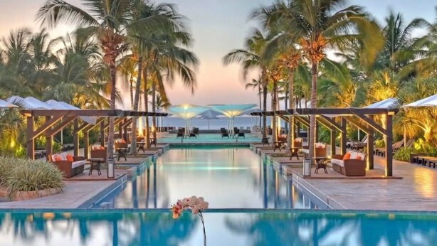 A pool area with lounge chairs and umbrellas, surrounded by palm trees. - Exclusive golf course view apartment in Buenaventura Golf & (El Chirú)