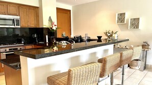 A modern kitchen with a central island, bar stools, stainless steel appliances, and decorative items. - Exclusive golf course view apartment in Buenaventura Golf & (El Chirú)