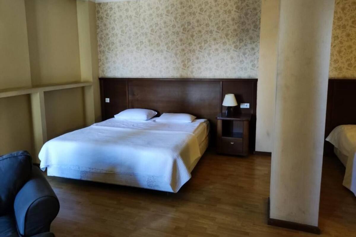Ein Hotelzimmer mit einem großen Bett, einem Nachttisch mit Lampe und einem Sessel.