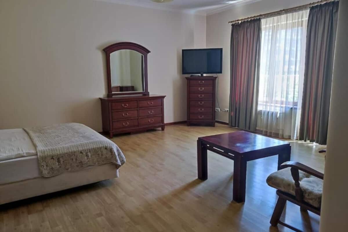 Ein Schlafzimmer mit einem Bett, einem Holzschrank, einem Fernseher und einem Tisch.