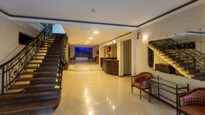 A spacious lobby with a curved staircase, a reception desk, and seating area. - Hotel Beaumonde Garden (Tbilisi)