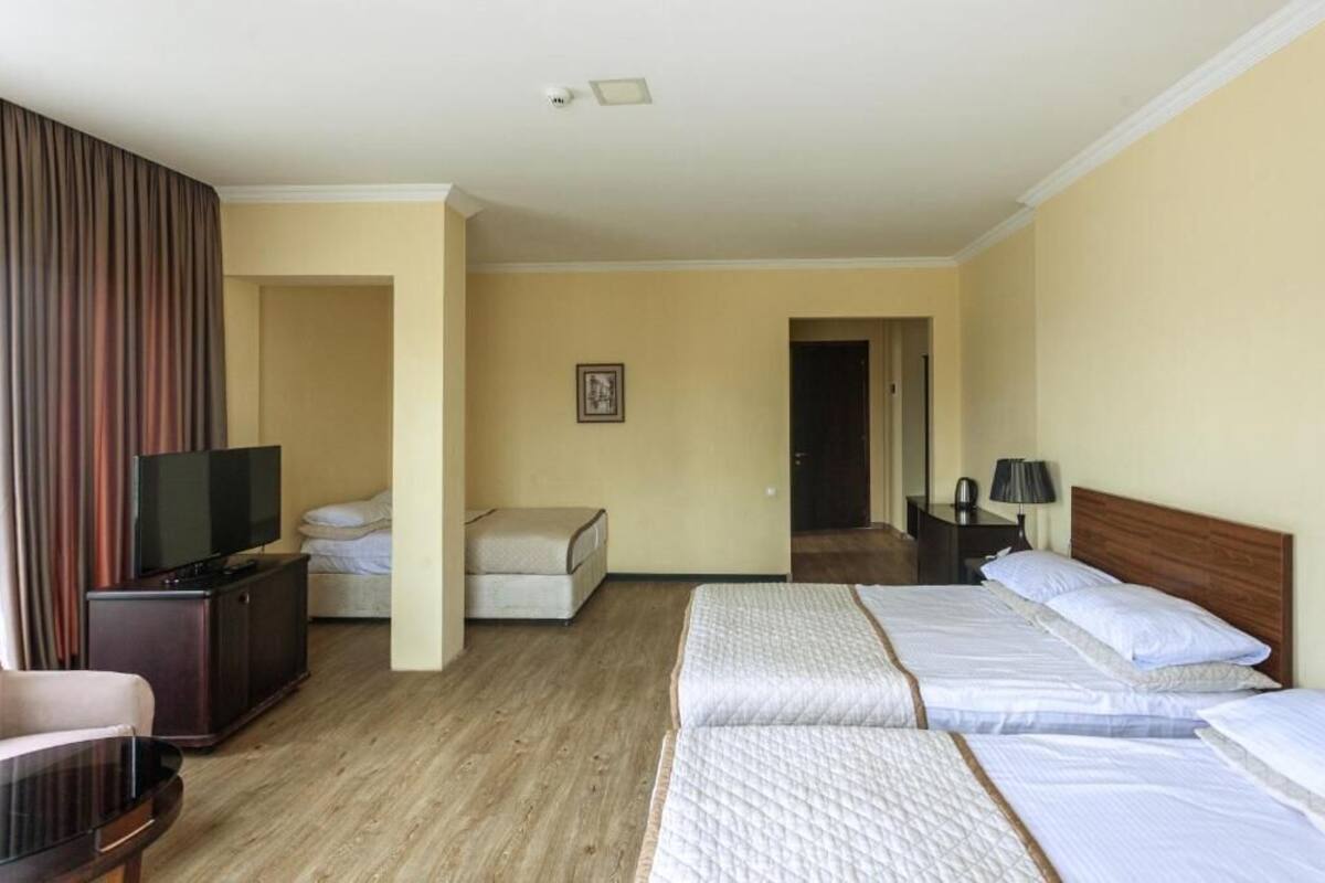 Ein Hotelzimmer mit zwei Betten, einem Fernseher, einem Schreibtisch und einem Sessel.