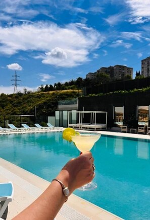 Una piscina al aire libre de temporada, sombrillas