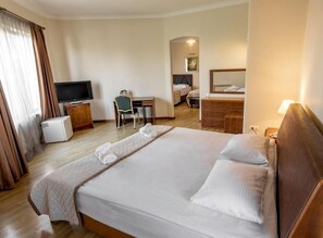 Ein Hotelzimmer mit einem großen Bett, einem Schreibtisch mit Stuhl, einem Fernseher und einer Kommode.