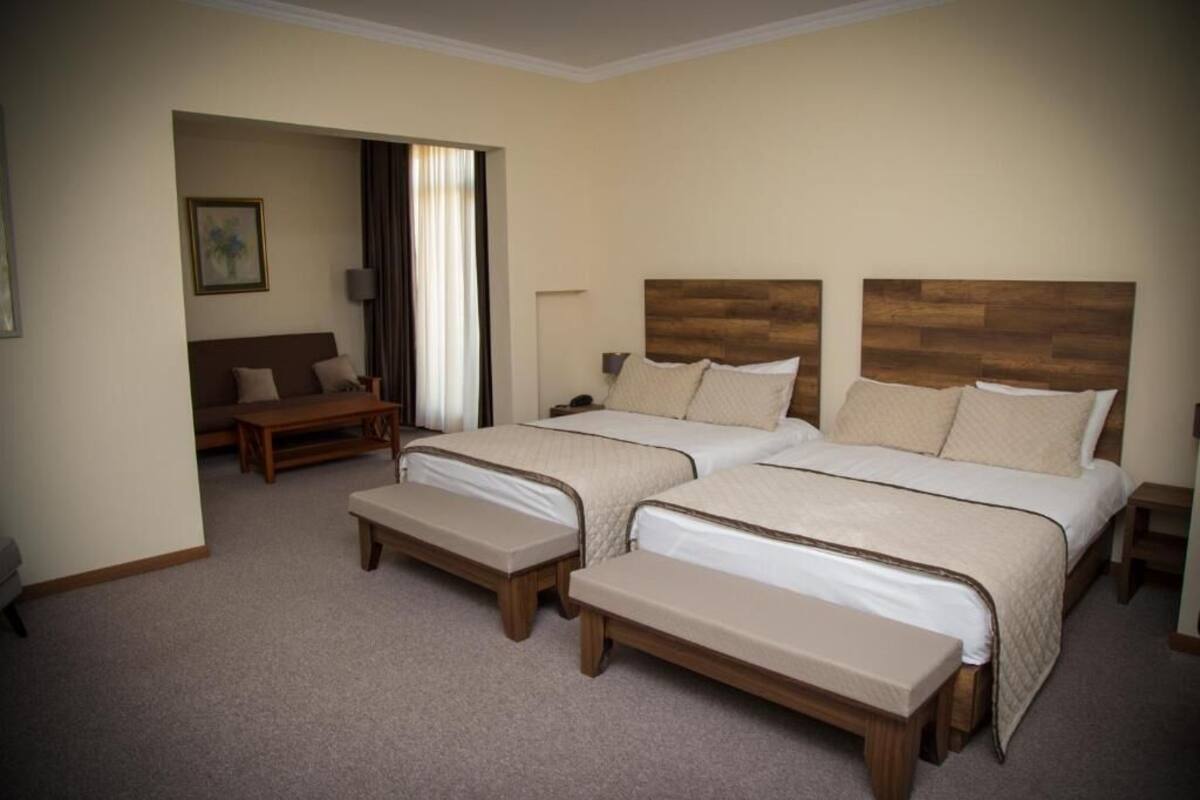 Ein Hotelzimmer mit zwei Betten, einer Couch und einer Bank.