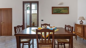 A dining area with a wooden table, chairs, and a painting on the wall. - 2141 Villetta Roberta - Piano Terra by Barbarhouse (Nardò)
