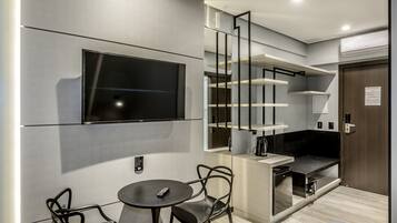 A modern kitchen with a built-in TV, a dining area with two chairs, and a staircase with open shelving.