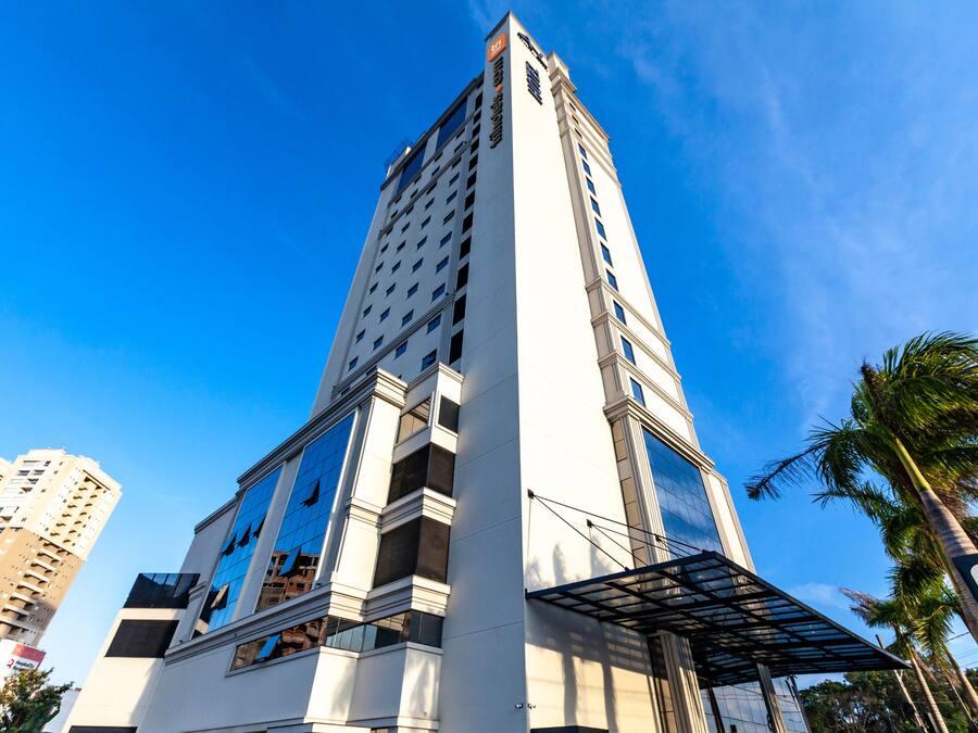 Um hotel alto com vários andares, janelas grandes e um design arquitetônico moderno.