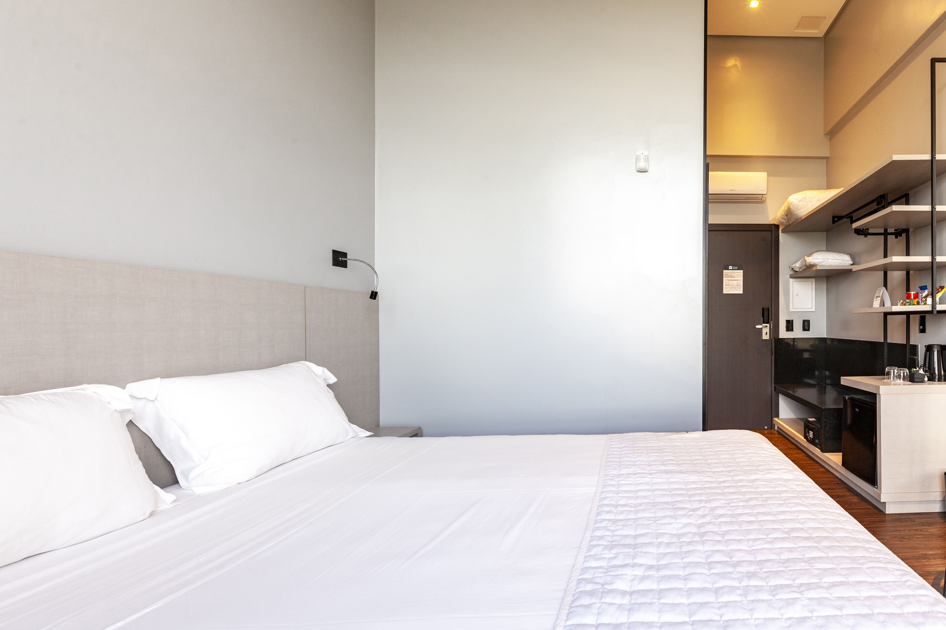 Une chambre d’hôtel moderne dotée d’un grand lit, d’un bureau intégré et d’une kitchenette.