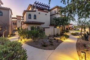 A residential area with a pathway leading to a house with a pergola and a patio.
