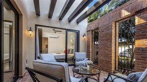 A patio area with outdoor seating, a glass door leading to a room, and a brick wall.