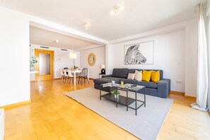 A modern living room with a grey sofa, a coffee table, and a dining area with a white table and chairs. - Myflats Luxury Navas (Alicante)