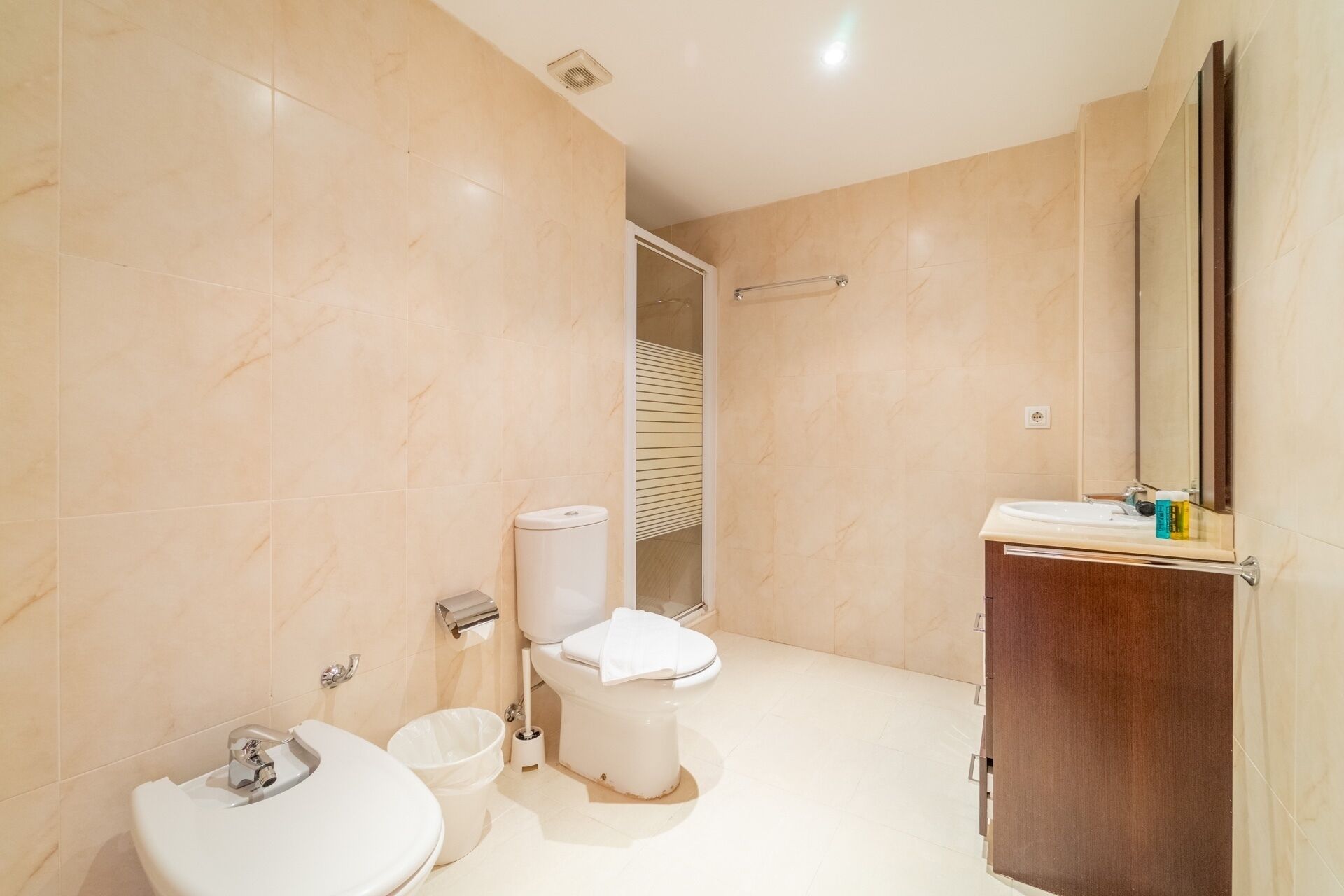 Un baño moderno con inodoro, bidé, lavamanos y espejo.
