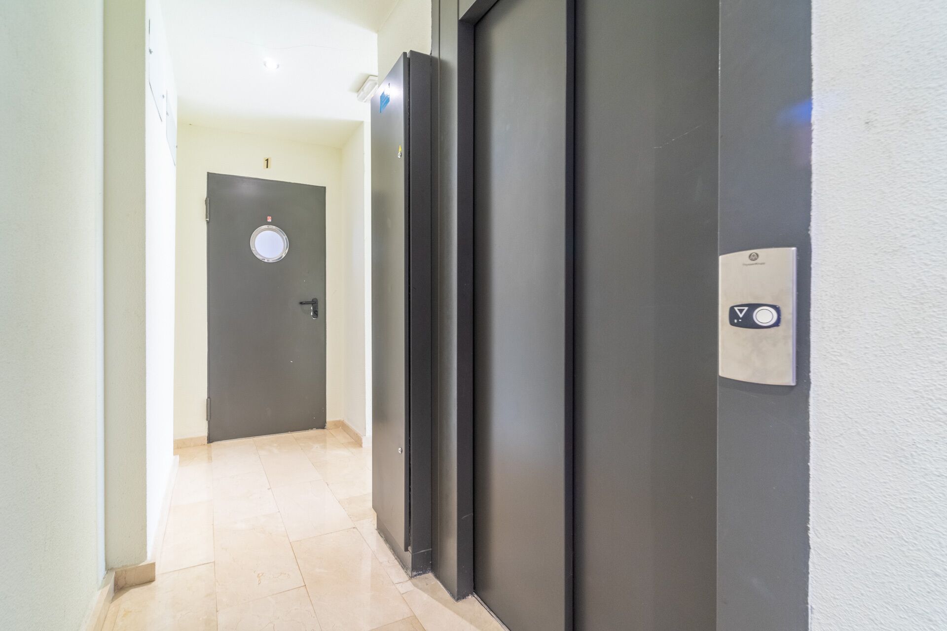 A hallway with a door marked '1' and a doorbell button.
