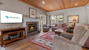 Una sala de estar acogedora con chimenea, asientos confortables y un televisor que muestra un logotipo.