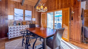 A wooden interior with a dining table, chairs, a chandelier, and artwork on the walls. - DESC09 - Retro Home, Sunken Living Room, Private Hot Tub (Sunriver)
