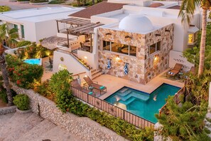 En moderne villa med swimmingpool, udendørs møbler og en facade af natursten.