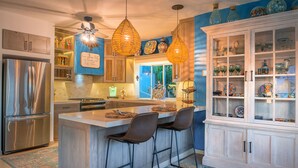 A modern kitchen with a central island, stainless steel appliances, and a decorative cabinet with glass doors. - Charming Cabo Villa w/ Heated Pool, Hot Tub, Firepit, Palapa & Ocean Views (Cabo San Lucas)
