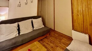 Ein gemütlicher Wohnbereich mit Sofa, einem kleinen Tisch und einer Holzwand.